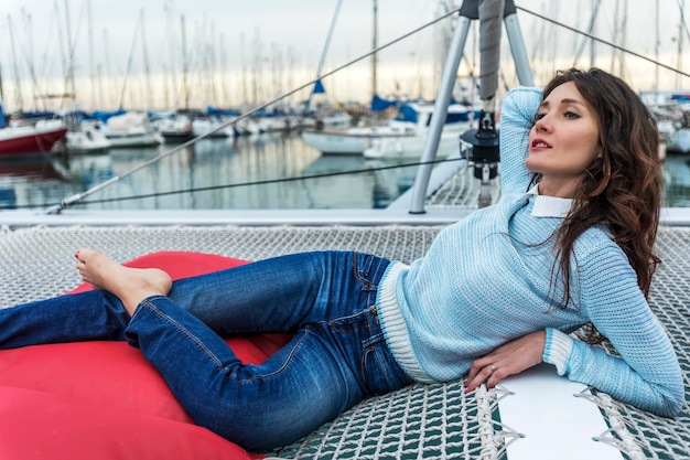 Beautiful woman lying on a catamaran while looking away at
barcelona harbor