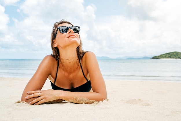 Bella donna sdraiata sulla sabbia della spiaggia