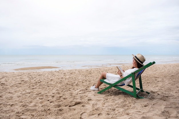 Una bella donna sdraiata e leggendo un libro sulla sedia a sdraio con una sensazione di relax