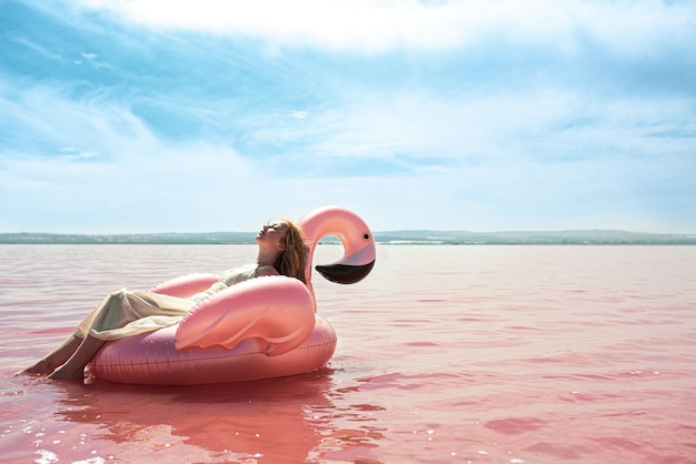 Beautiful woman lying on inflatable float mattress on pink sea