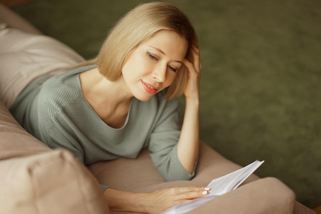 Una bella donna sdraiata su un divano a leggere un libro lifestyle photography