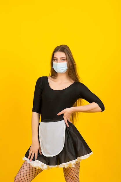 Beautiful  woman in maid clothes posing in studio in covid protective mask