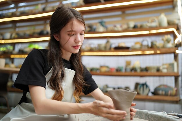 Beautiful woman making ceramic pottery on wheel hands closeup woman in freelance business hobby