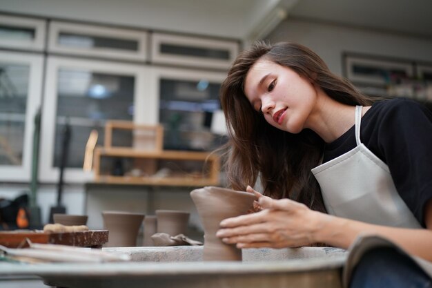 Beautiful woman making ceramic pottery on wheel hands closeup woman in freelance business hobby