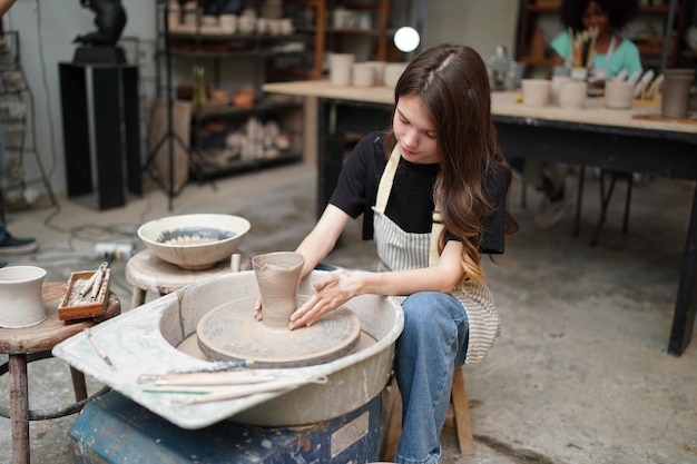 Beautiful woman making ceramic pottery on wheel hands closeup woman in freelance business hobby