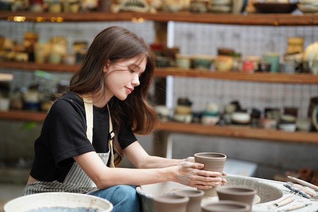 Beautiful woman making ceramic pottery on wheel hands closeup woman in freelance business hobby