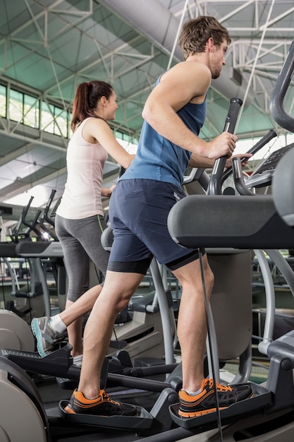 Beautiful woman and man exercising on the elliptical machine