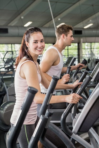 Beautiful woman and man exercising on the elliptical machine