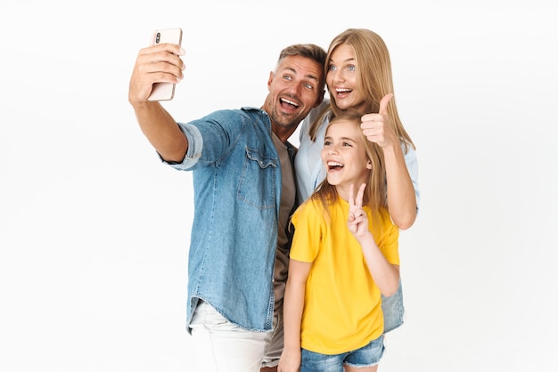 Photo beautiful woman and man with little girl smiling while taking selfie on cellphone isolated on white