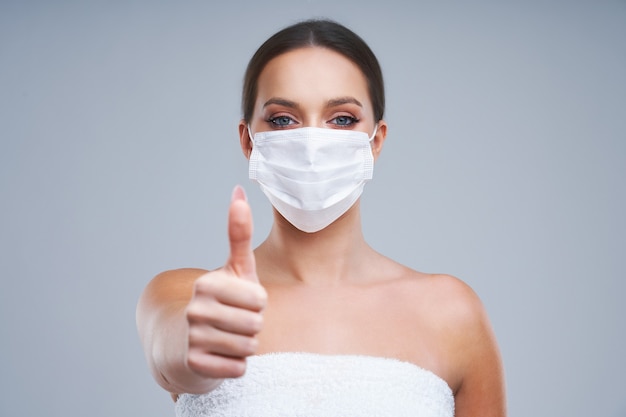 beautiful woman in mask on gray background