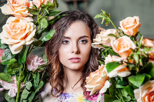 Beautiful woman model in the colors of the roses in garden with a beautiful makeover