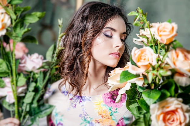 Beautiful woman model in the colors of the roses in garden with a beautiful makeover