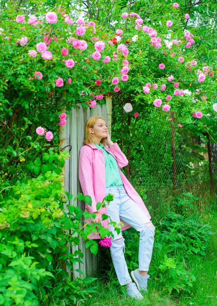 Beautiful woman near pink roses in garden beautiful girl in blooming garden elegant lady in blossom