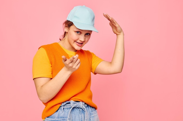 Beautiful woman in an orange sweater in blue caps hand gesture cropped view unaltered