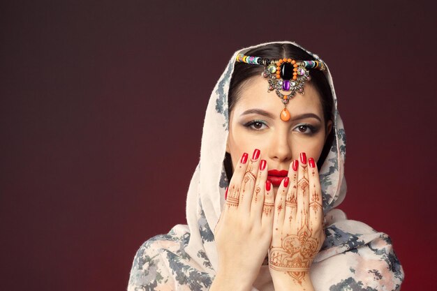 Beautiful woman in oriental style with mehendi on dark background