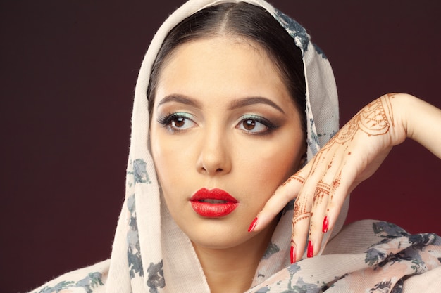 Beautiful woman in oriental style with mehendi on dark