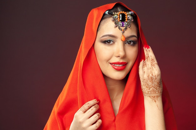 Beautiful woman in oriental style with mehendi on dark