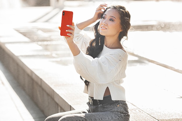Beautiful woman outdoors Pretty lady on urban background Asian female closeup portrait Woman making selfie