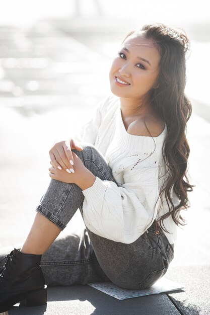 Beautiful woman outdoors. Pretty lady on urban background. Asian female closeup portrait.