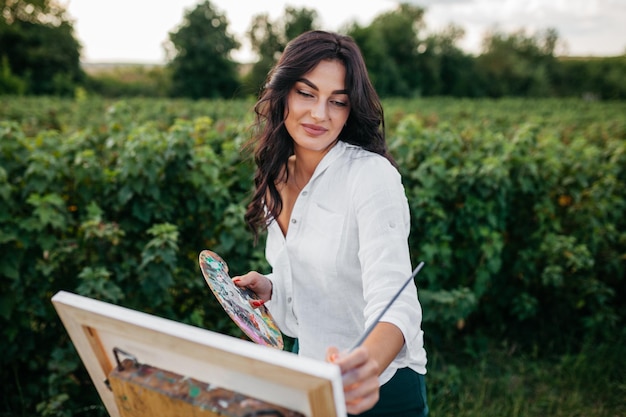 Beautiful woman painting in the field