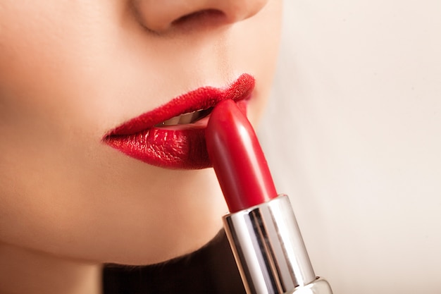 La bella donna dipinge le labbra con rossetto.