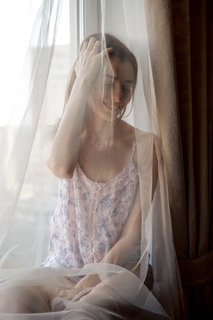 Beautiful woman in pajama sitting on windowsill