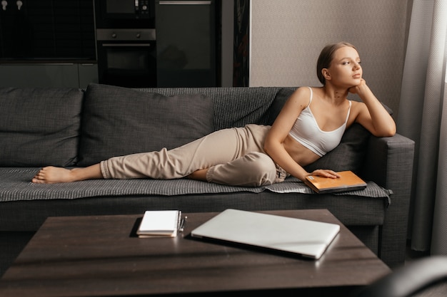 Beautiful woman in pants and a top lying on the sofa