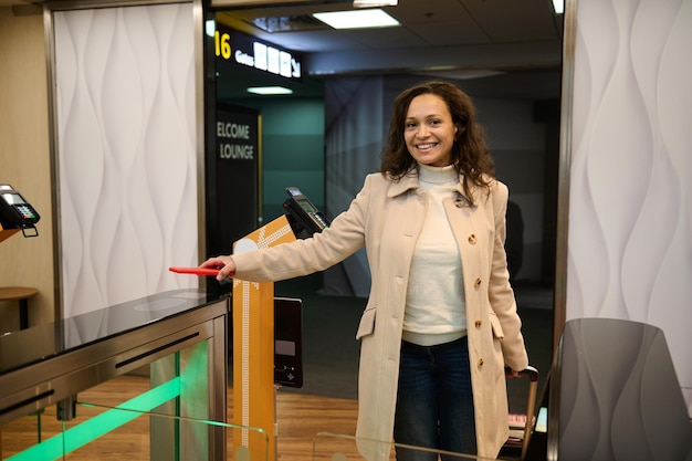 Beautiful woman passenger scanning information on the phone by placing it over the scanner to read the QR-codes at the check-in counter while entering the VIP lounge in the airport departure terminal