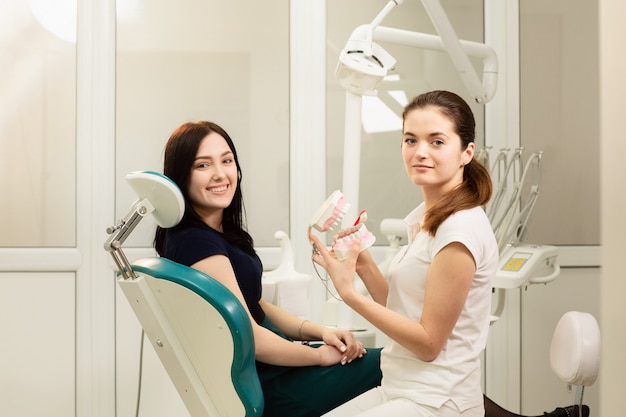 Красивый пациент женщины имея лечение зубов на офисе дантиста. доктор держит медицинскую челюсть