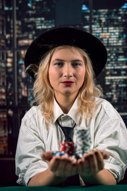 Beautiful woman player plays poker and looks at cards and chips