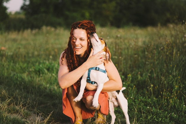 Красивая женщина играет со своей собакой Джек Рассел в парке Концепция дружбы животных с людьми и любовью женщина лежит на траве и играет с джек рассел терьером