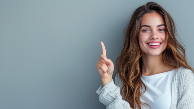 Photo beautiful woman pointing to the side smiling gray background