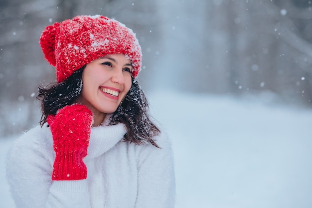 Bello ritratto della donna all'aperto nello spazio della copia della foresta innevata