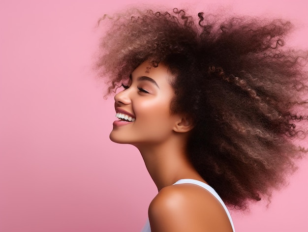 beautiful woman portrait with afro hair in profile smiling on pink background