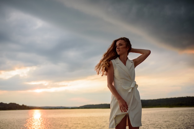 Beautiful woman posing by the lake at sunset