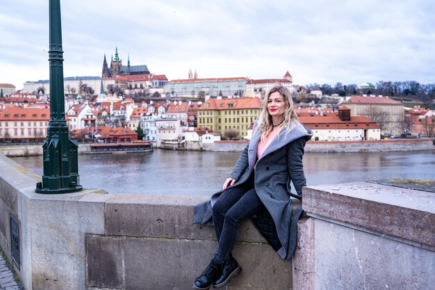 beautiful woman posing on the Charles Bridge on the background of Prague Castle