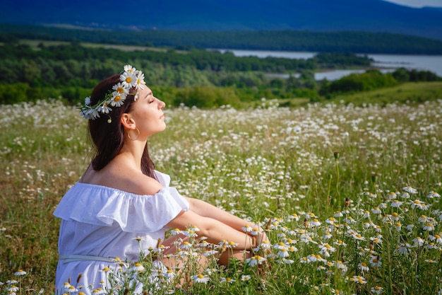 Beautiful woman posing on a field with daisies