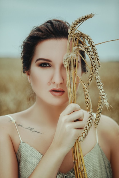 Beautiful woman posing in the golden wheat field