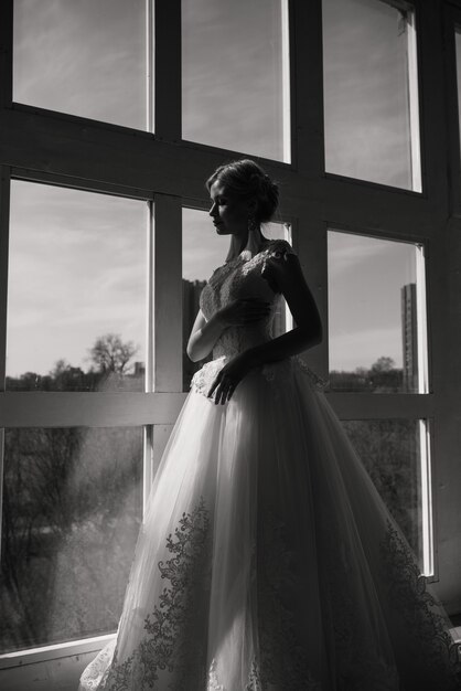 The beautiful woman posing in a wedding dress in luxury interior
