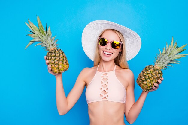 Красивая женщина позирует с ананасами и солнцезащитными очками