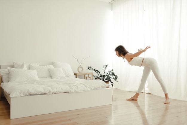 Bella donna che pratica yoga a casa. donna al mattino che fa yoga in camera da letto.