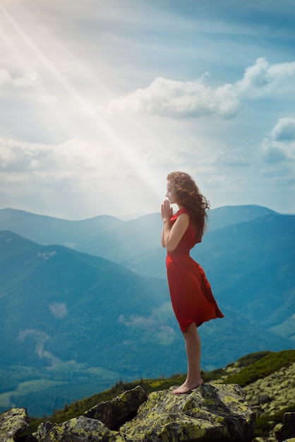 Bella donna che prega nel paesaggio di montagna