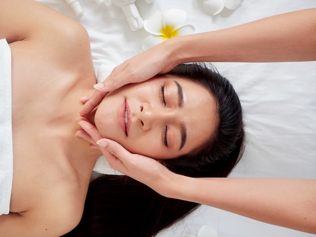 Beautiful woman receiving facial massage in spa.