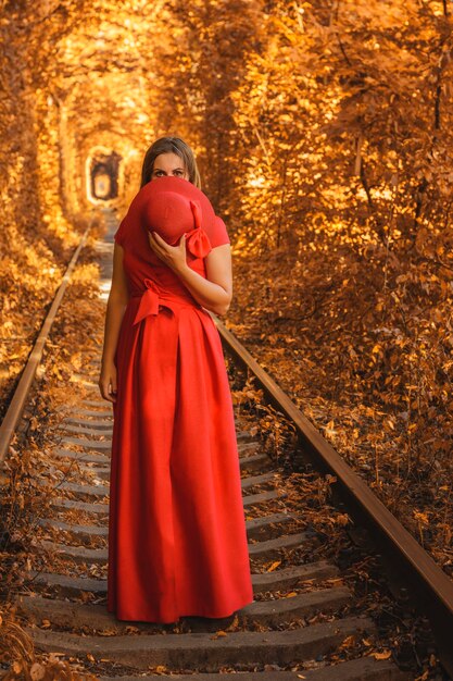 Beautiful woman in red autumn dress walks the tunnel of love