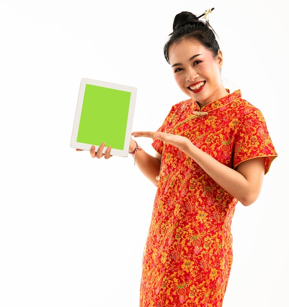 A beautiful woman in red cheongsam standing pointed to the tablet at her hand and smiling showing he