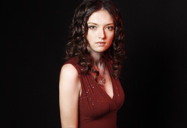 beautiful woman in red dress with evening make-up .isolated on black wall