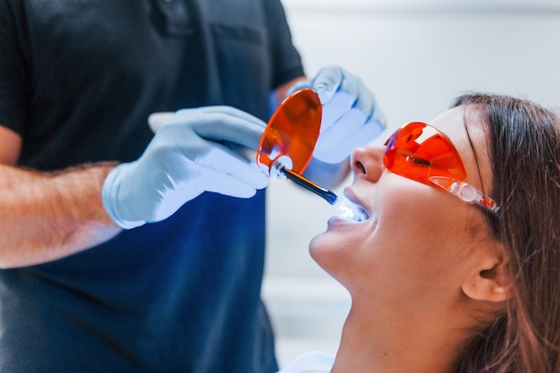 Beautiful woman in red protective glasses have a visit in the dentist clinic. Conception of stomatology.