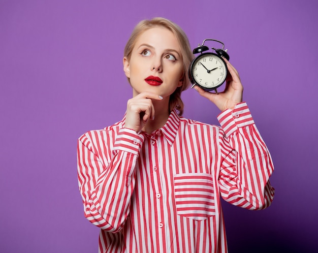 Beautiful woman in red striped shirt with alarm clock  