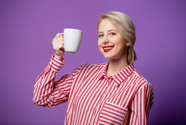 一杯のコーヒーと赤い縞模様のシャツの美しい女性