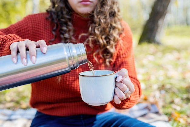 Beautiful woman in red sweater on a picnic in a autumn forest